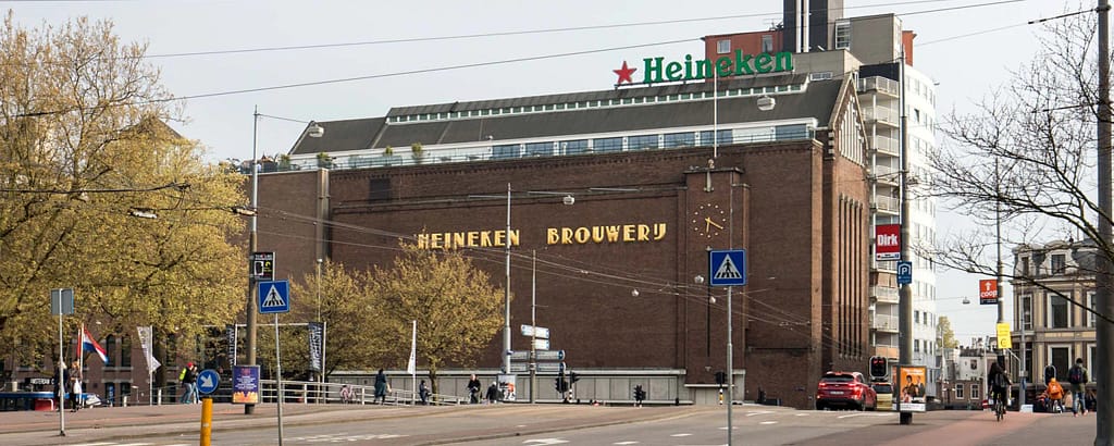 Exterior view of the Heineken Brewery in Amsterdam with green Heineken sign and surrounding street
