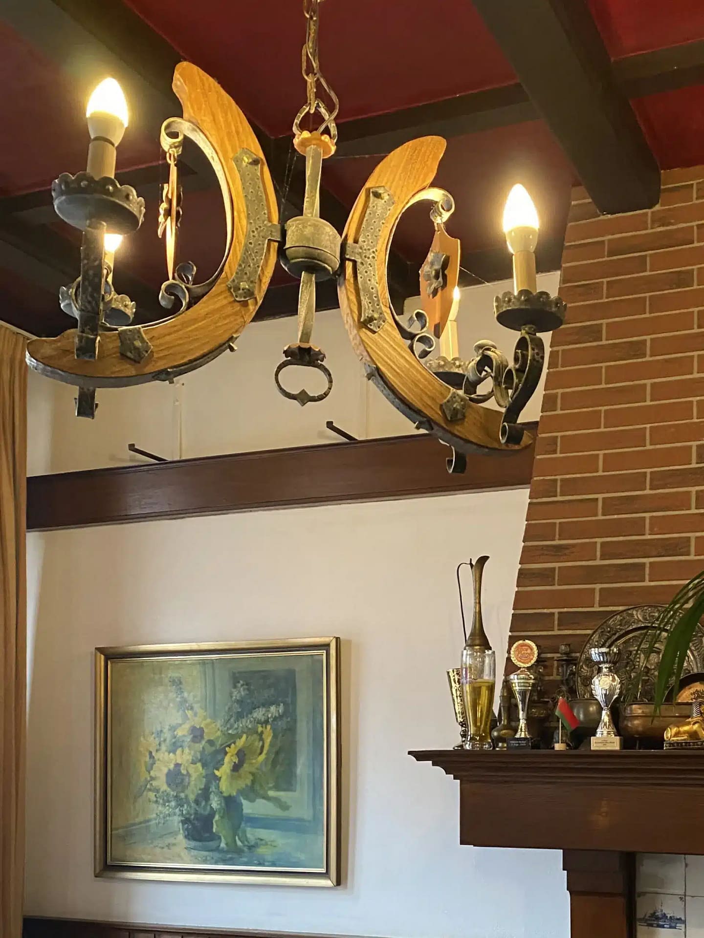 Cozy lounge area in Budget Hotel Sphinx Amsterdam with a rustic chandelier, sunflower painting, and trophy display.