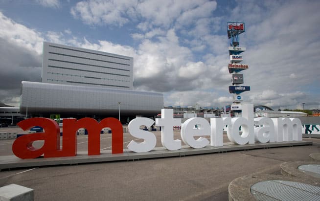 Amsterdam RAI building with the 'amsterdam' sign in the foreground. The sign rotates around different locations in Amsterdam and is conveniently accessible from Sphinx Hotel Amsterdam.